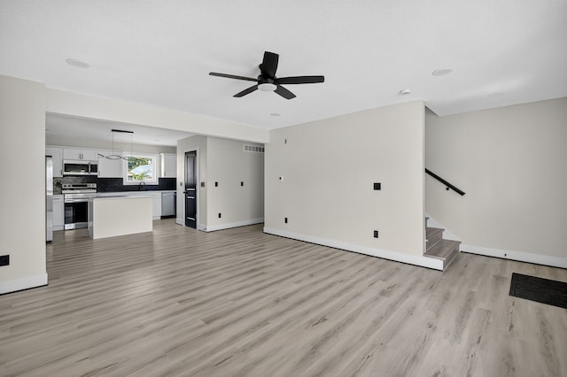 1218 Mccormick St, Des Moines, IA 50316 - unfurnished living room with a ceiling fan, light wood-type flooring, and stairs