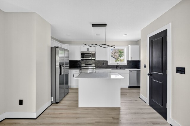 1218 Mccormick St, Des Moines, IA 50316 - kitchen featuring stainless steel appliances, decorative backsplash, a center island, white cabinetry, and light wood-style flooring
