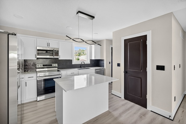 1218 Mccormick St, Des Moines, IA 50316 - kitchen featuring stainless steel appliances, light wood finished floors, backsplash, white cabinetry, and a kitchen island
