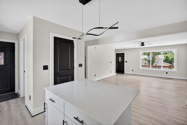 1218 Mccormick St, Des Moines, IA 50316 - kitchen featuring light wood-style floors, a center island, white cabinets, light stone counters, and open floor plan