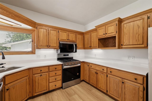 204 N Gaines St, Stuart, IA 50250 - kitchen with stainless steel appliances, light wood finished floors, brown cabinetry, and light countertops