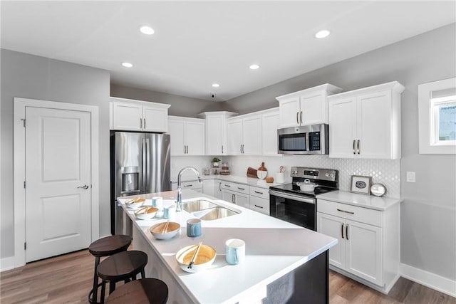 kitchen featuring a center island with sink, appliances with stainless steel finishes, sink, and hardwood / wood-style flooring