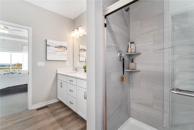 bathroom with a shower with shower door, hardwood / wood-style flooring, vanity, and ceiling fan