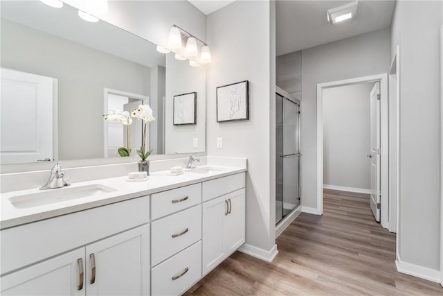 bathroom featuring a shower with shower door, hardwood / wood-style floors, double sink, and large vanity