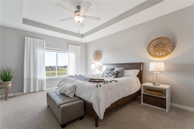 bedroom featuring ceiling fan, a raised ceiling, and carpet flooring