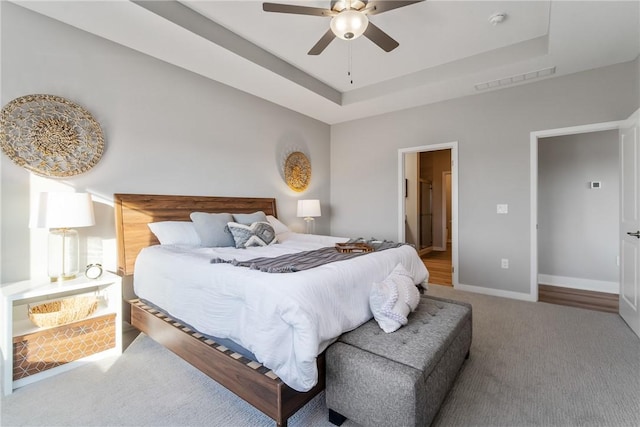 bedroom with wood-type flooring, ceiling fan, and a raised ceiling