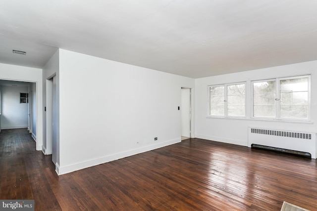 unfurnished room featuring radiator heating unit and dark hardwood / wood-style floors