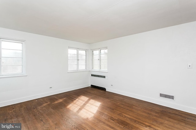 empty room with radiator and dark hardwood / wood-style floors