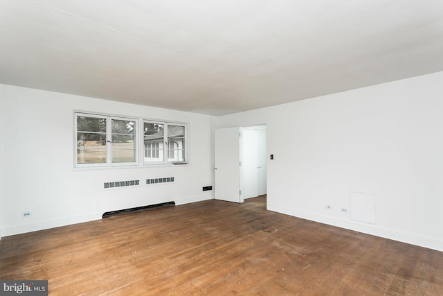 spare room with hardwood / wood-style floors and radiator heating unit