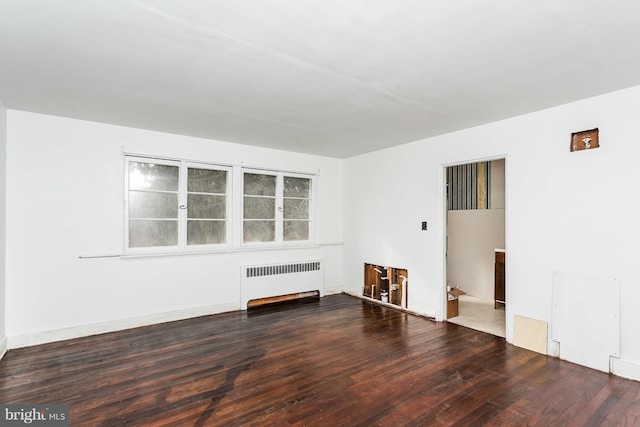 unfurnished living room with dark hardwood / wood-style flooring and radiator