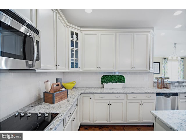 kitchen featuring tasteful backsplash, light stone countertops, white cabinets, and stainless steel appliances