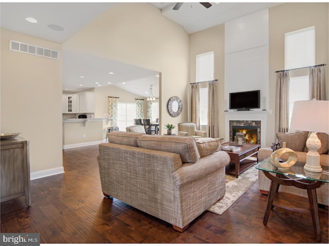 living room with a high end fireplace, ceiling fan with notable chandelier, dark hardwood / wood-style floors, and high vaulted ceiling