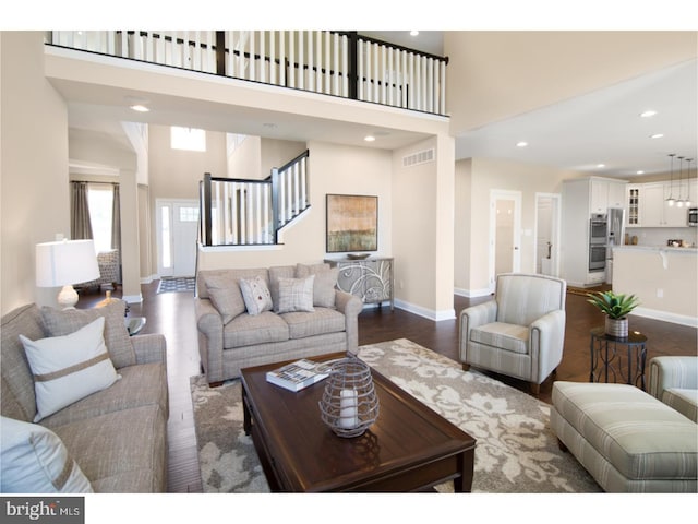 living room featuring dark wood-type flooring and a high ceiling