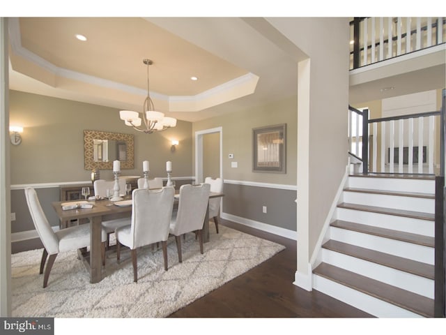 dining space featuring wood-type flooring, a tray ceiling, and a notable chandelier