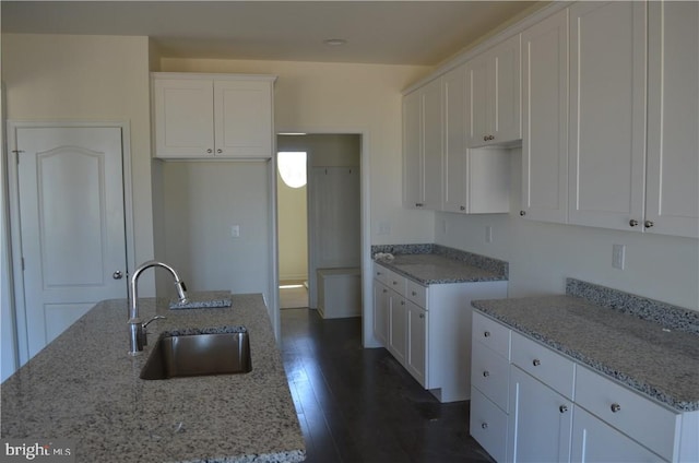 kitchen with white cabinets, dark hardwood / wood-style flooring, a center island with sink, and sink