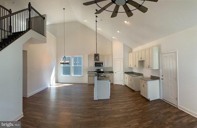 kitchen with decorative light fixtures, ceiling fan with notable chandelier, dark wood-type flooring, and high vaulted ceiling