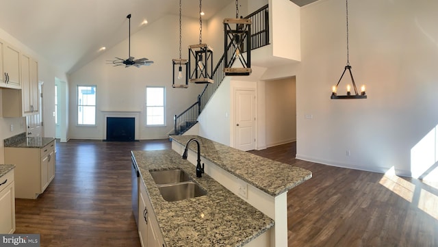 kitchen with dark hardwood / wood-style flooring, light stone counters, sink, high vaulted ceiling, and a kitchen island