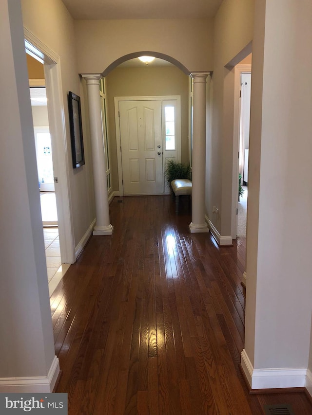 corridor with dark hardwood / wood-style flooring and ornate columns