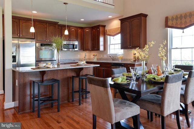 kitchen with hanging light fixtures, light stone countertops, a center island, and appliances with stainless steel finishes