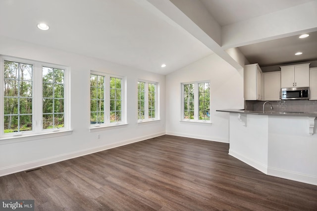 kitchen with a kitchen bar, kitchen peninsula, white cabinetry, and dark wood-type flooring