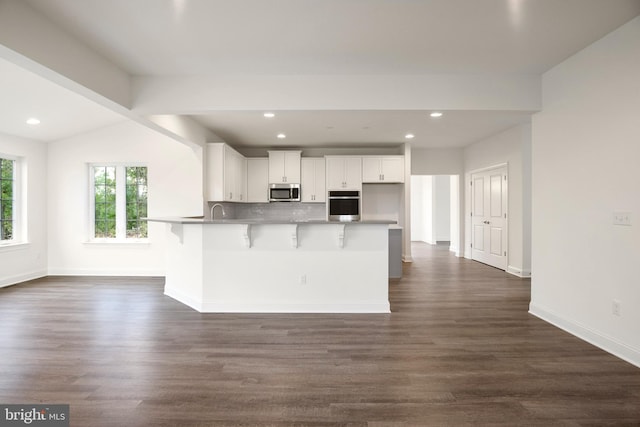 kitchen featuring white cabinetry, dark hardwood / wood-style floors, lofted ceiling, a breakfast bar area, and appliances with stainless steel finishes