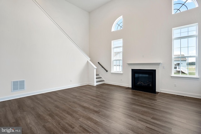 unfurnished living room with a towering ceiling and dark hardwood / wood-style floors