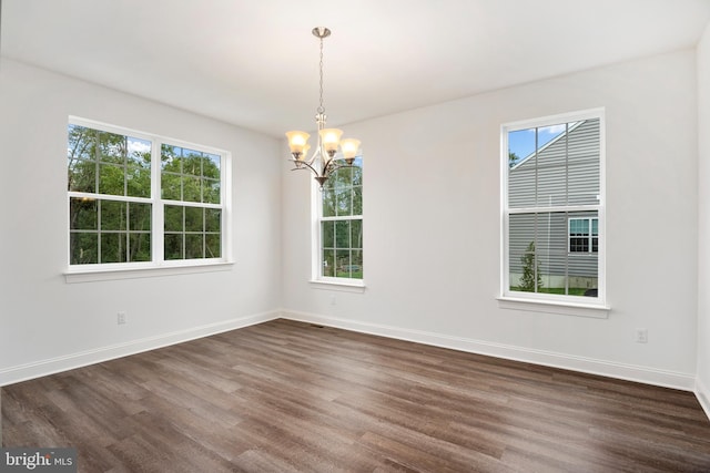 empty room featuring a notable chandelier and dark wood-type flooring