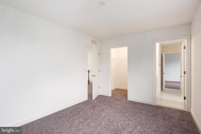 unfurnished bedroom featuring a walk in closet, a closet, and carpet