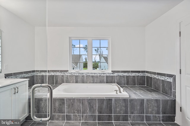 bathroom with tile patterned flooring, vanity, and tiled bath