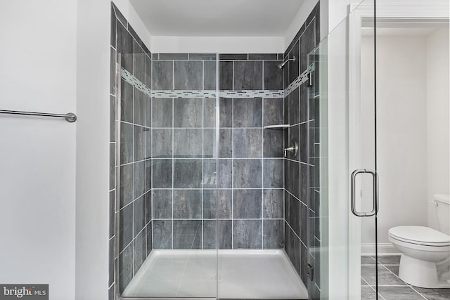 bathroom with tile patterned floors, a shower with door, and toilet