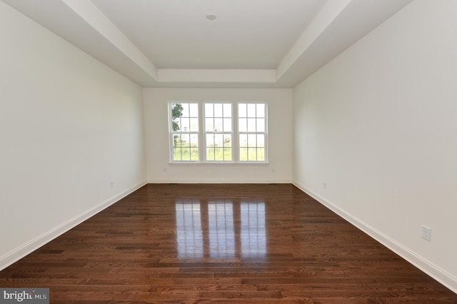 empty room with dark hardwood / wood-style floors and a raised ceiling