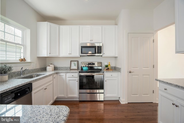 kitchen with sink, stainless steel appliances, white cabinets, and light stone countertops