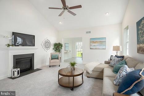 living room featuring ceiling fan, a healthy amount of sunlight, high vaulted ceiling, and light carpet