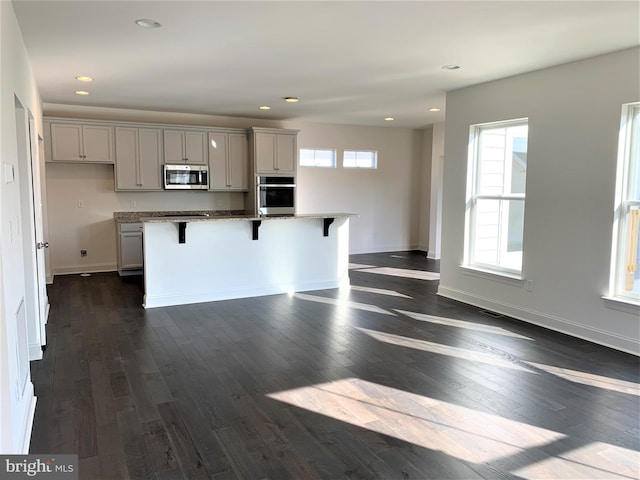 kitchen featuring a kitchen breakfast bar, an island with sink, a healthy amount of sunlight, and appliances with stainless steel finishes