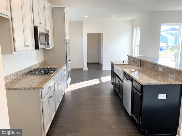 kitchen featuring stainless steel appliances, sink, a center island with sink, dark hardwood / wood-style floors, and white cabinetry