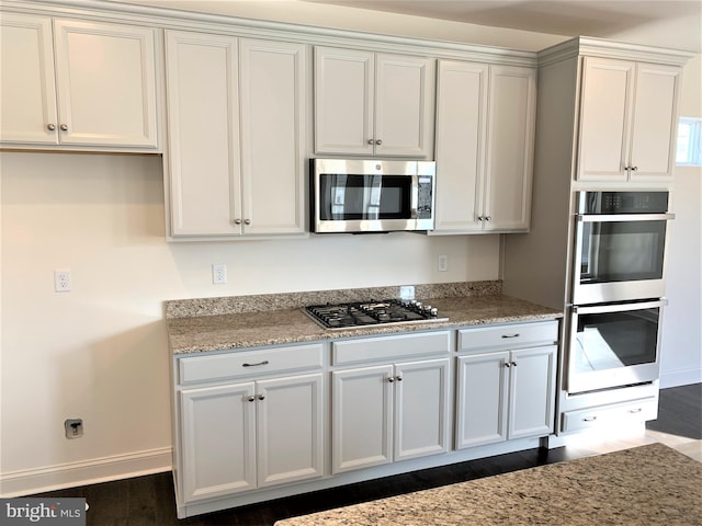 kitchen featuring white cabinetry, light stone counters, dark wood-type flooring, and stainless steel appliances