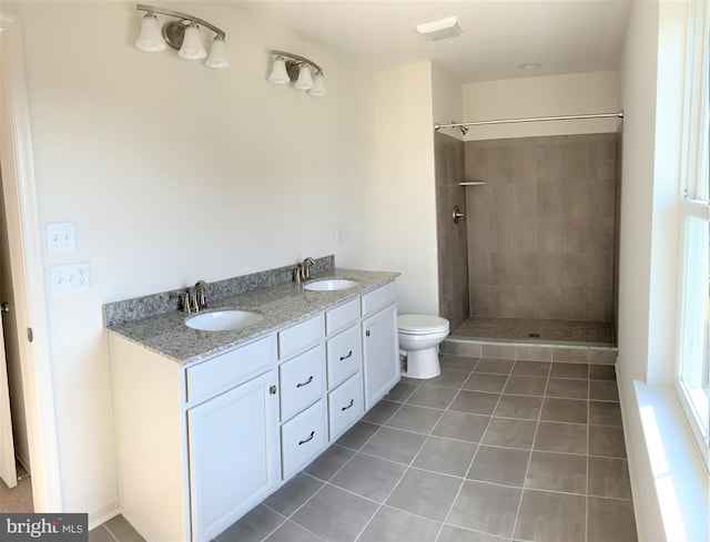 bathroom featuring tile patterned flooring, vanity, toilet, and tiled shower