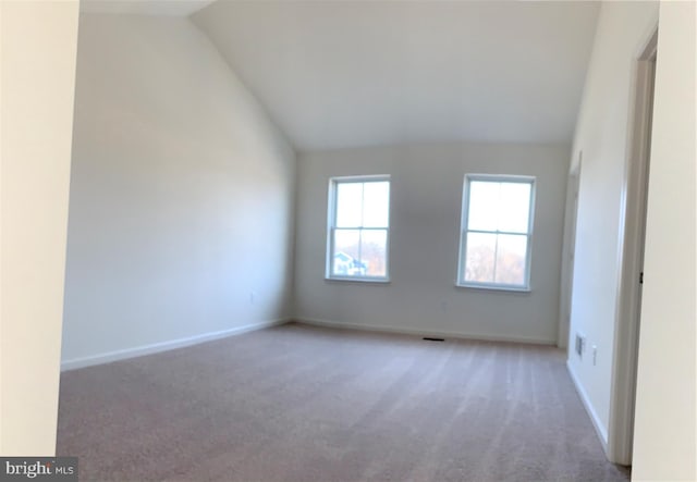 carpeted empty room with lofted ceiling