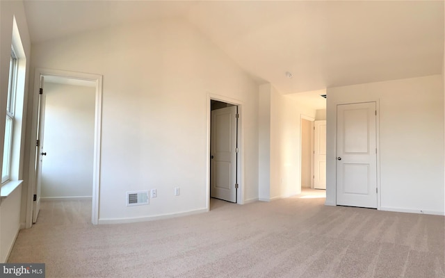 carpeted empty room with lofted ceiling