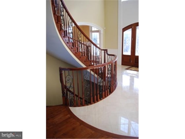 stairway with french doors and wood-type flooring