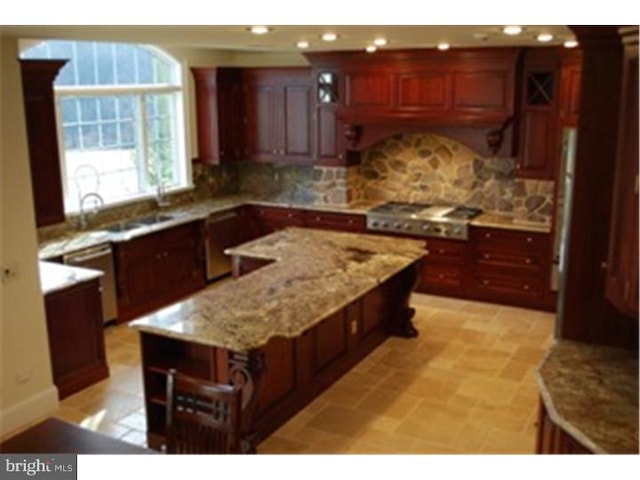 kitchen featuring light stone countertops, decorative backsplash, a kitchen island, and stainless steel gas stovetop