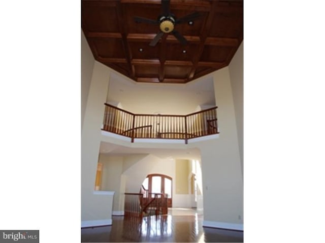 stairs with wood-type flooring, a high ceiling, coffered ceiling, and wood ceiling