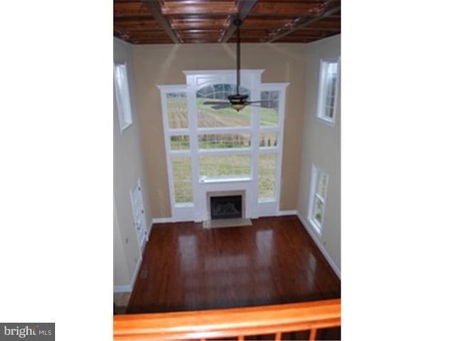 unfurnished dining area featuring ceiling fan, beam ceiling, wood-type flooring, and wooden ceiling