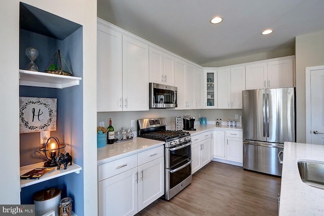 kitchen featuring white cabinets, light stone counters, wood-type flooring, and stainless steel appliances