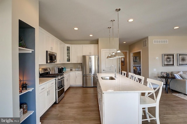 kitchen featuring a kitchen bar, appliances with stainless steel finishes, sink, hanging light fixtures, and an island with sink