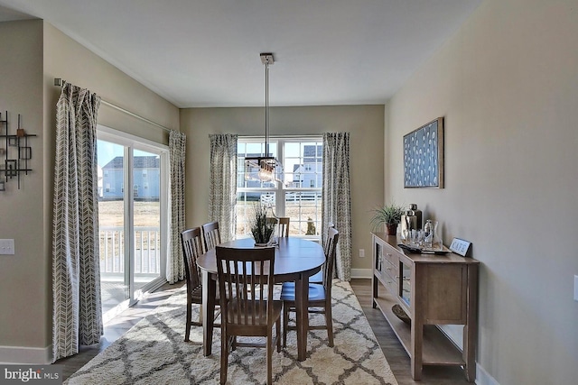 dining room with hardwood / wood-style floors, a healthy amount of sunlight, and an inviting chandelier