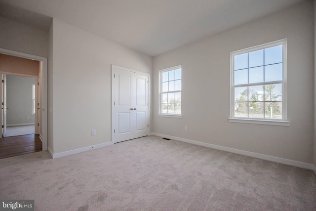 unfurnished bedroom with multiple windows and light colored carpet