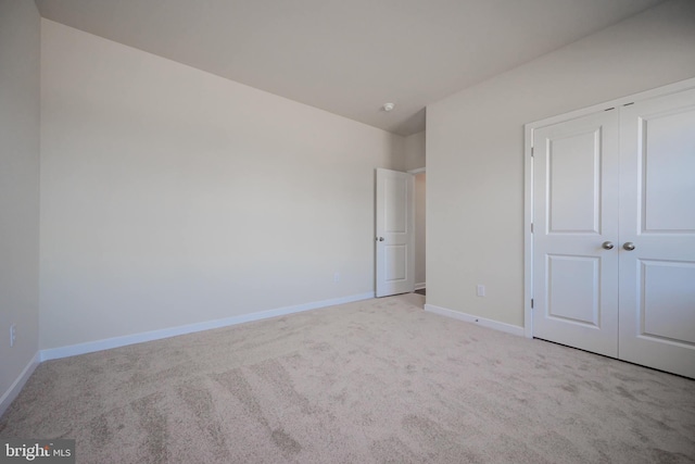 unfurnished bedroom featuring a closet and light colored carpet