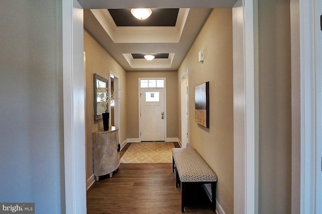 entryway with a raised ceiling, dark wood-type flooring, and ornamental molding