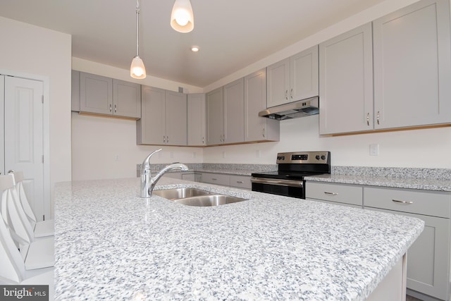 kitchen with sink, stainless steel electric range oven, an island with sink, decorative light fixtures, and light stone counters